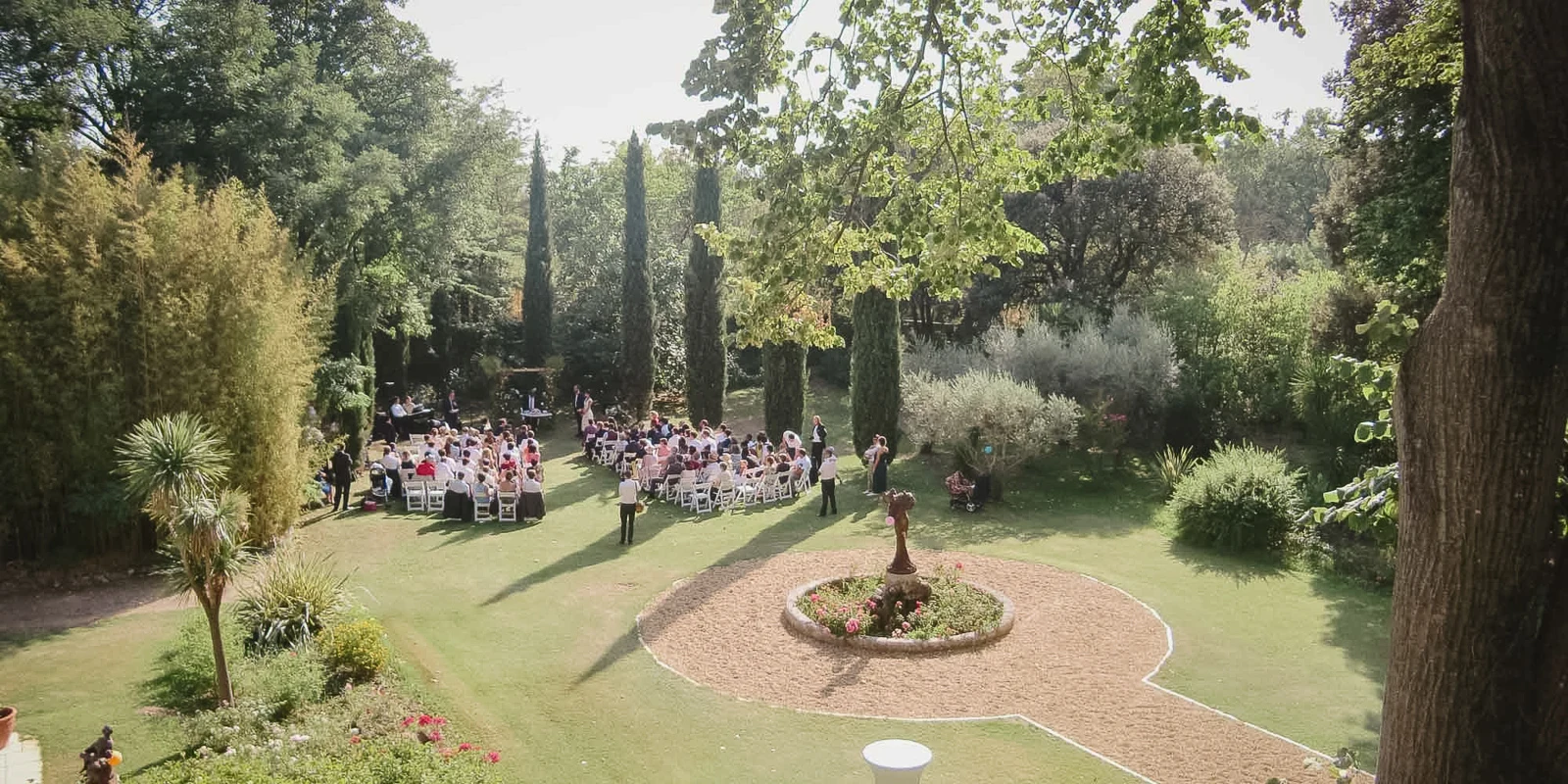 Hochzeitsgesellschaft im mediterranen Schlossgarten der Provence mit Zypressen und Springbrunnen